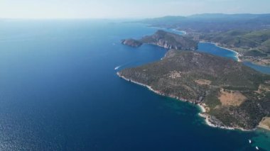 Avrupa 'nın Grece kentinde yeşil ağaçlı Sithonia yarımadasındaki mavi deniz suyunun havadan görünüşü. Pelerinin drone görüntüsü