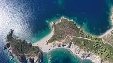 Avrupa 'nın Grece kentinde yeşil ağaçlı Sithonia yarımadasındaki mavi deniz suyunun havadan görünüşü. Pelerinin drone görüntüsü