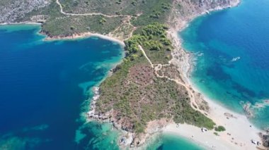 Avrupa 'nın Grece kentinde yeşil ağaçlı Sithonia yarımadasındaki mavi deniz suyunun havadan görünüşü. Pelerinin drone görüntüsü