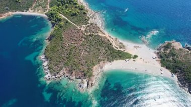Avrupa 'nın Grece kentinde yeşil ağaçlı Sithonia yarımadasındaki mavi deniz suyunun havadan görünüşü. Pelerinin drone görüntüsü
