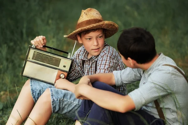 A Guy In A Straw Hat Invites A Friend To Listen To A Vintage Radio. — Stock fotografie