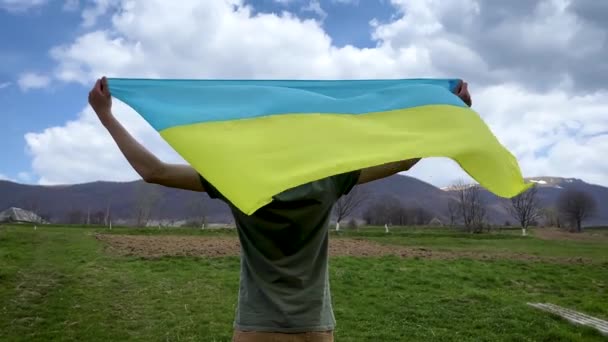 Een man houdt de Oekraïense vlag vast en kijkt naar de lege verschroeide aarde. Stop de oorlog.. — Stockvideo