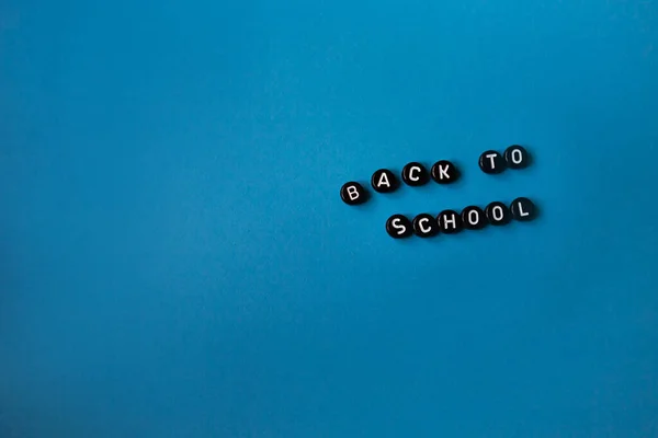 Inscrição de letras pretas De volta à escola em um fundo azul isolado. Espaço de cópia. — Fotografia de Stock
