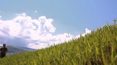Light-skinned male runner running from grass top of mountain hill. Healthy man jogging 