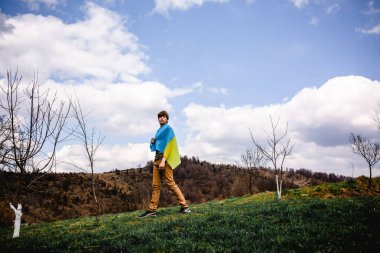 Bir adam Ukrayna bayrağını tutuyor. Savaşı durdurun. Dağların arkasında..