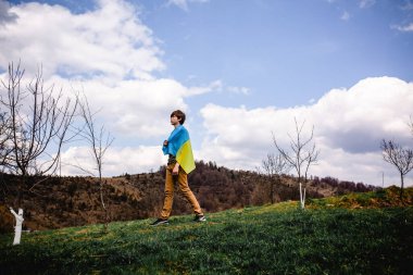 Bir adam Ukrayna bayrağını tutuyor. Savaşı durdurun. Dağların arkasında..