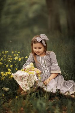 Klasik elbiseli bir kız elinde küçük bir tavuk tutuyor..