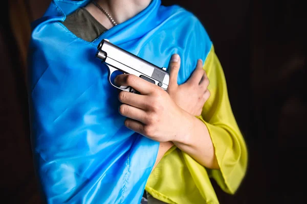 En hand med ett vapen på bakgrunden av den ukrainska flaggan. Blodig hand. — Stockfoto