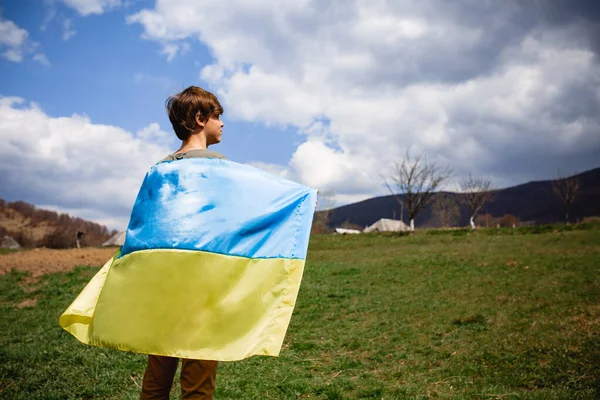 Bir adam Ukrayna bayrağını tutuyor. Savaşı durdurun. Dağların arkasında..