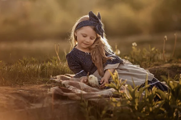 Antika elbiseli bir kız çimenlerde yatar ve tavuğa bakar..