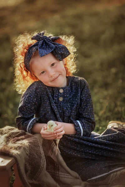 Kızıl saçlı bir kız tavuk tutuyor..