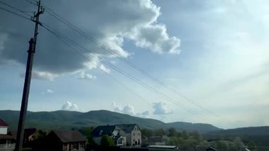 Geçen bir arabanın penceresinin dışındaki dağlardaki köy manzarası..