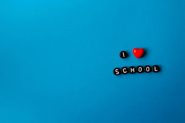 Inscription of black letters Back to school. I love school on an isolated blue background. Copy space. — Photo