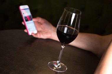 Elinde kırmızı şarapla akıllı telefona bakan bir adam. Yüksek kalite fotoğraf