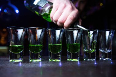 Ahşap tezgahta bardaklara içki döken bir barmenin ellerinin yakın fotoğrafını çek. Yüksek kalite fotoğraf