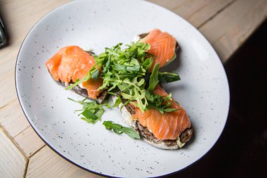Beyaz tabakta somon ve roka salatası.