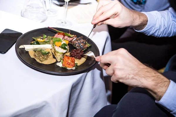 Kadın eli bıçaklı bir tabak ve beyaz arka planda kaşıklı bir çatal tutuyor.