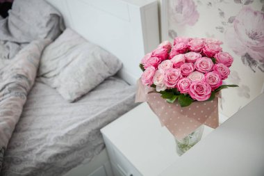 beautiful pink roses in a white bed with a bouquet of flowers