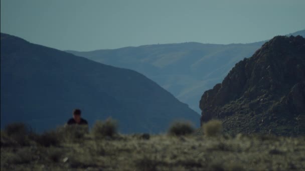 その努力をした男は カリフォルニアの日没の光線の砂漠地帯の斜面を自転車で登る 山は地平線に見える 奴は集中できない ロサンゼルス — ストック動画
