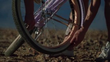 Adamın biri ezildi, kamerayı tekerleğe taktı, elleriyle bisiklete bindi ve aniden düştü. Kayalık bir çöl bölgesinde, güneş ışınlarında sorun var. Kaliforniya Amerika. HD film görüntüleri