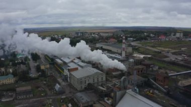 4K hava görüntüleri küçük bir kasabada bir fabrika. Katlı üretim, lojistik, bacadan çıkan dumanı görebilirsiniz, hava kirliliği, kömür, hurda metal, çöp. Küçük bir köyde sanayi bölgesi.