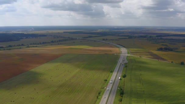 4Kの航空ビュー映像高速道路 草の色のフィールドと干し草の小屋の間に トラックは道路 車のドライブの側面に駐車されます 雲の影が空にかかっている — ストック動画