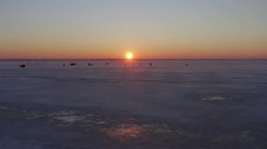 4K hava görüntüsü. Kar Mutfağı ekibi paraşütlerini katlıyor çünkü güneş batıyor ve eve dönme zamanı geldi. Batan güneş turuncu ufkun altına iniyor. Buz mora döndü.. 