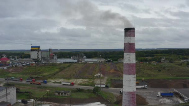 4K市の郊外にある工場の空中映像 手前の空気を汚染する煙管 物流プロセス トラック原料 ウクライナの国旗を背景に — ストック動画