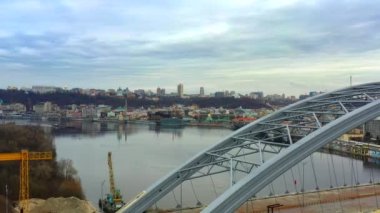 Dnieper Nehri 'ne ve Kyiv' in sağ kıyısına bakan bitmemiş bir köprünün yanından 4K uçuş görüntüsü. Hilly Kyiv eklektizminin modern ve eski mimari görüşleri. Traffet. Ukrayna 