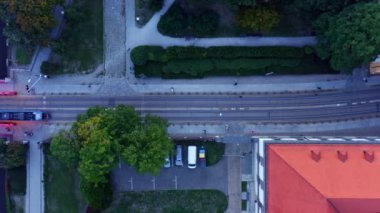 4k yukarıdaki hava görüntüsü modern tramvay yolu bir yaz akşamı Odre nehri yakınlarındaki St. Johns Katedrali ve parkı boyunca hareket eder. Yeşil ağaçların altında yürüyen insanlar. Yılan pençesi. Polonya 