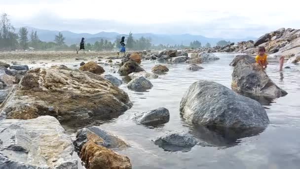 Çocuklar Deniz Taşlarının Etrafında Oynayarak Tatillerinin Tadını Çıkarıyorlar — Stok video