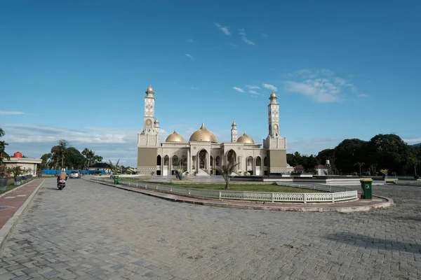 Aceh Barat Daya, Endonezya - 6 Ağustos 2022 Aceh Barat Daya Büyük Camii altın bir kubbesi olan gümüş bir araba ve Blangpidie 'de geçen bir motosikletle görkemli bir şekilde duruyor.