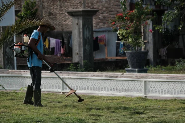 Aceh Barat Daya, Endonezya - 6 Ağustos 2022 Çim biçme makinesi sabah Blangpidie, Aceh Barat Daya 'da bir çim biçme makinesiyle çim biçiyor.
