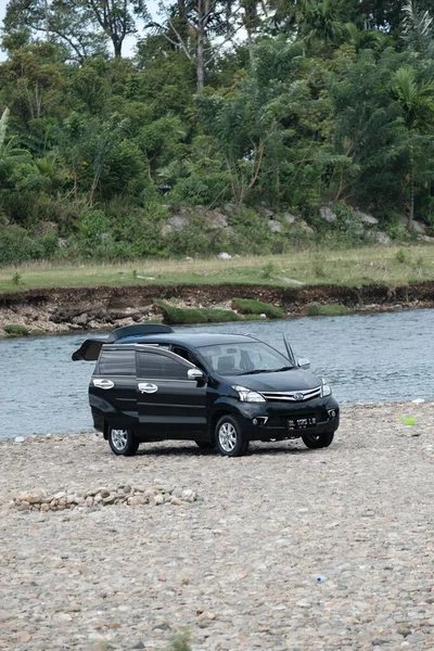 Aceh Barat Daya, Endonezya - 6 Ağustos 2022 Blangpidie 'de bulunan bir nehrin kenarında yeni yıkanmış siyah bir Toyota avanza arabası dikey olarak fotoğraflanmıştır.