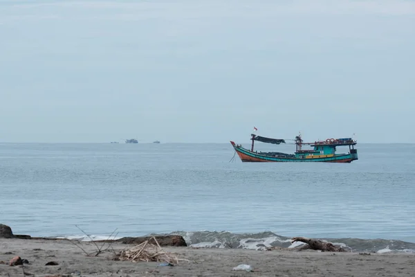 Aceh Barat Daya, Endonezya - 7 Ağustos 2022 Mavi deniz suyu ve Susoh Abdya 'daki karayı gösteren küçük bir balıkçı teknesi