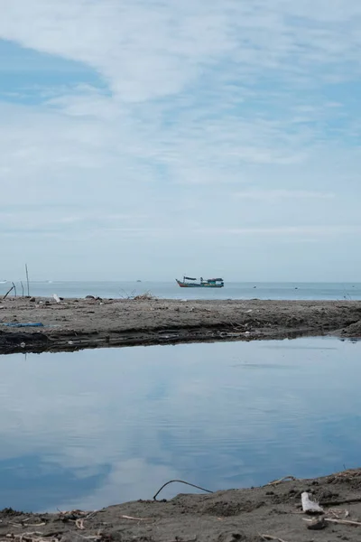 Aceh Barat Daya, Endonezya - 7 Ağustos 2022 Susoh Abdya 'daki mavi deniz suyu ve karayı gösteren küçük bir balıkçı teknesi dikey olarak fotoğraflandı.
