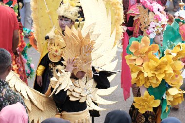 Banda Aceh, Endonezya - 18 Ağustos 2022 Küçük bir çocuk kuş kaskı tutuyor Sarı kuş kostümüyle karnaval geçidine katılıyor