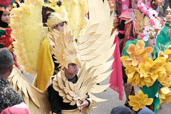 Banda Aceh, Endonezya - 18 Ağustos 2022 Endonezya bağımsızlık günü festivalinde karnaval geçit törenine katılan bir çocuk geniş sarı kanatlı eşsiz bir kostüm giyer.