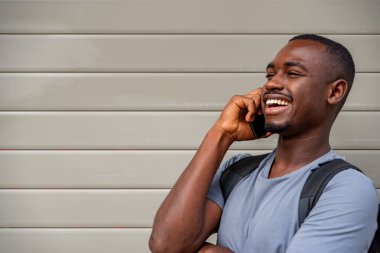 Duvara karşı cep telefonu kullanan Afro genç adam.