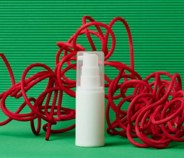 Yeşil arka planda kozmetik malzemesi olarak kullanılan beyaz plastik şişe. Marka ürünleri için boş, nemlendirici, maket.