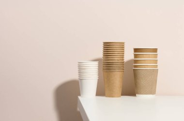 Kahve ve çay için kağıt karton beyaz ve kahverengi fincanlar, bej arka plan. Çevre dostu sofra takımı, sıfır atık