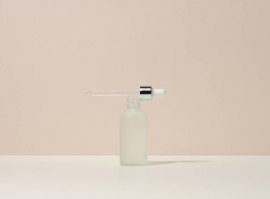 Pipetli beyaz cam şişe bej arka planda duruyor. Kozmetik SPA markası. Jel, serum, reklam ve ürün tanıtımı için ambalaj, maket