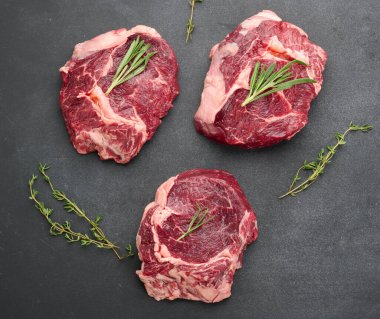 Biberiyeli çiğ sığır pirzolası, siyah bir masada kekik.