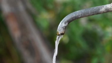 Sokaktaki eski metal bir borudan gelen su akıntısı.