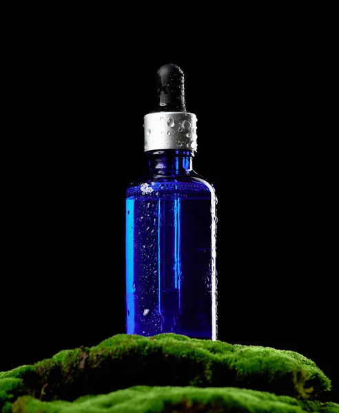 Blaue Glasflasche Mit Pipettenständer Auf Grünem Moos Schwarzem Hintergrund Cosmetics — Stockfoto