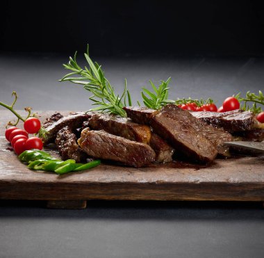 Kızarmış biftek parçalarını eski kahverengi bir doğrama tahtasıyla parçalara ayırdım. Lezzetli biftek, yakın çekim.