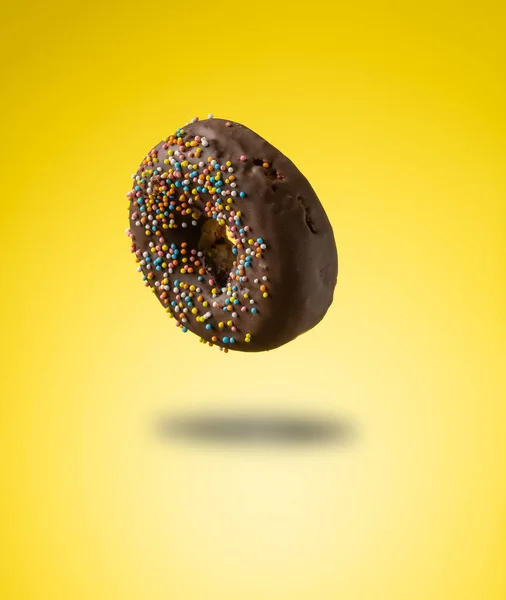 Chocolade Donuts Met Veelkleurige Hagelslag Zweven Een Gele Achtergrond — Stockfoto
