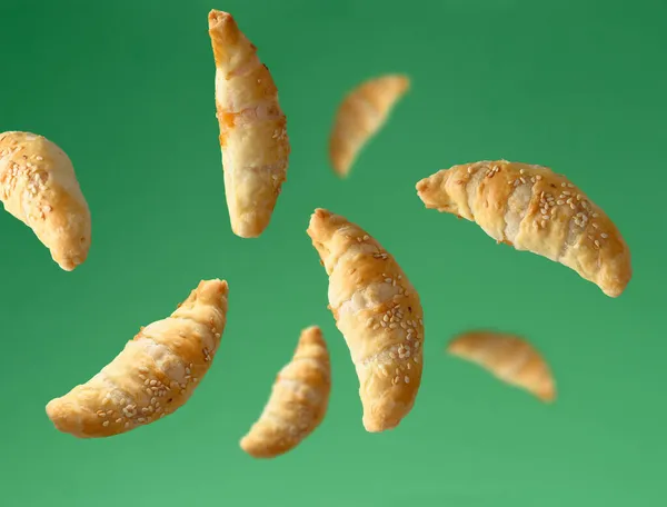 Mini Croissants Voadores Polvilhados Com Sementes Gergelim Fundo Verde — Fotografia de Stock