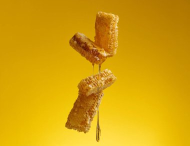 Sarı arkaplanda bal peteğinin üzerinden akan bal