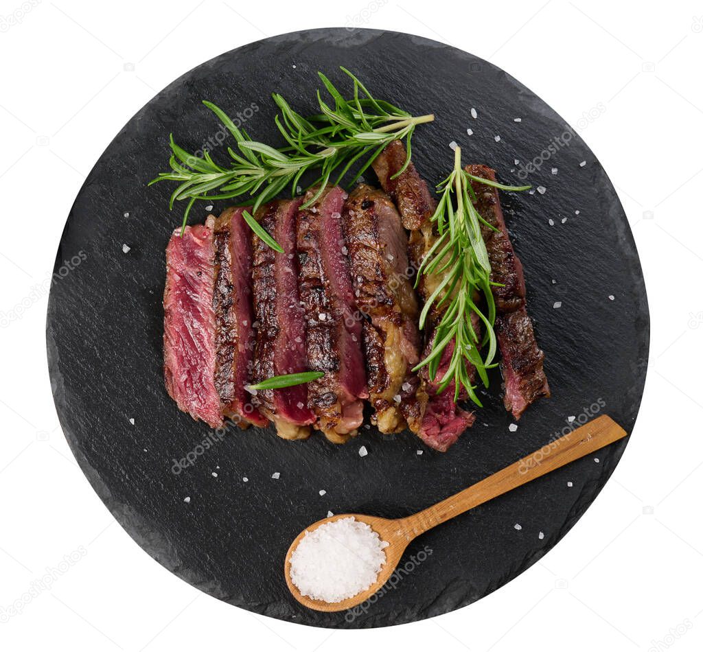 fried piece of beef ribeye cut into pieces on a black board, rare degree of doneness. Delicious steak, top view